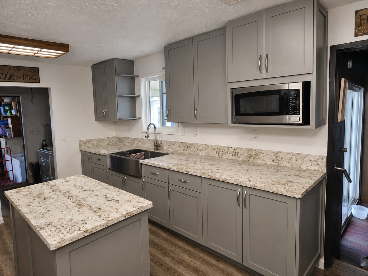 Gray shaker kitchen with a stainless farmhouse sink, granite counters, and an island